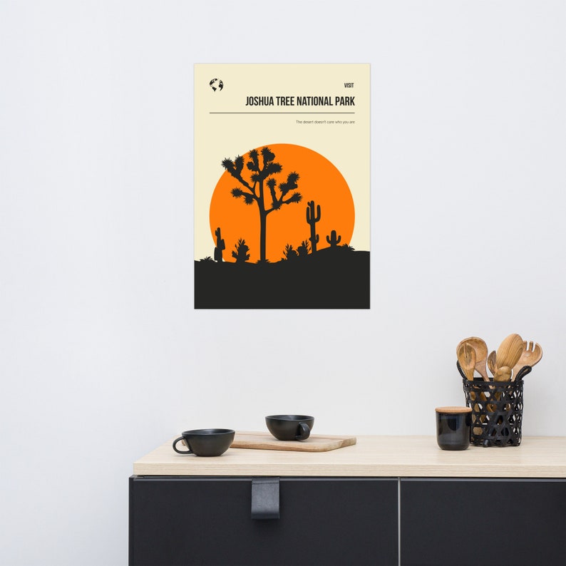 May include: A minimalist poster with a black silhouette of a Joshua Tree and a large orange sun against a cream background. The text "Joshua Tree National Park" is in black at the top of the poster.