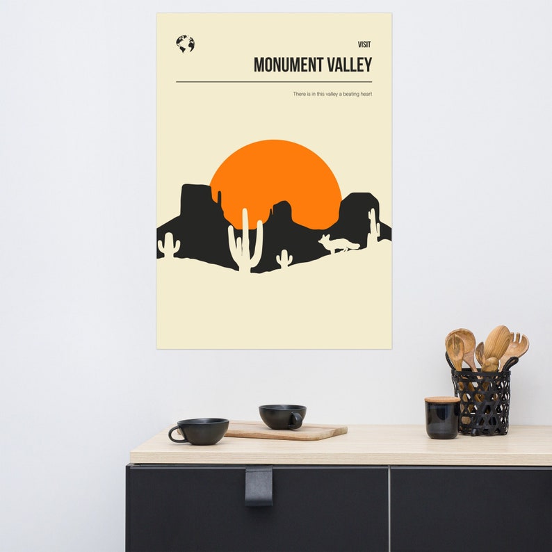 Peut inclure: Une affiche minimaliste avec un fond beige repr&eacute;sentant une silhouette noire d'un paysage d&eacute;sertique avec un soleil couchant. Le texte "VISIT MONUMENT VALLEY" est en haut de l'affiche, et le texte "There is in this valley a beating heart" est en dessous du paysage.