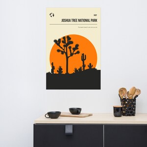 May include: A minimalist poster with a black silhouette of a Joshua Tree and a bright orange sunset. The text "VISIT JOSHUA TREE NATIONAL PARK" is at the top of the poster. The text "The desert doesn't care who you are" is below the image.