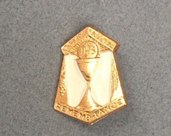 May include: Gold-colored metal pin with a chalice and host design. The pin has the words "In Loving Remembrance" inscribed on it.
