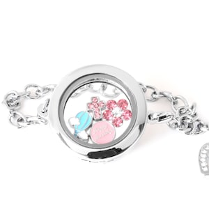 May include: A silver locket bracelet with a heart charm. The locket is open and contains pink and blue charms, including a charm that says "Happy Birthday".