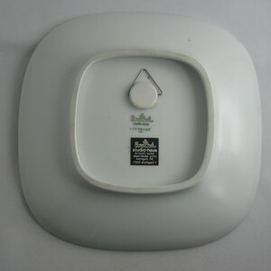 May include: White square ceramic plate with a green and black label that reads "studio-haus, keramik-werke, k&ouml;nigstr. 49, 7000 stuttgart 1".