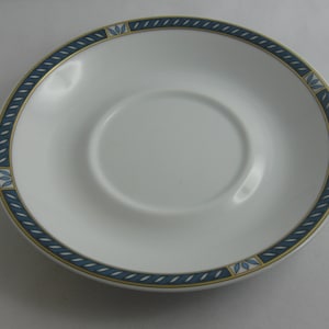 May include: A white saucer with a blue and gold border. The border has a rope design with small blue and gold leaves.