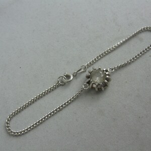 May include: A silver chain bracelet with a clear stone set in a silver bezel.