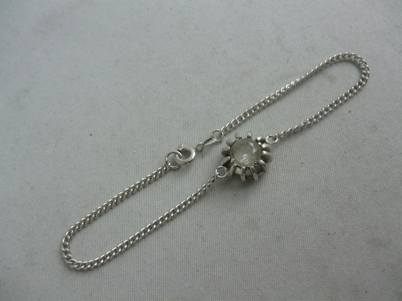 May include: A silver chain bracelet with a clear stone set in a silver bezel.