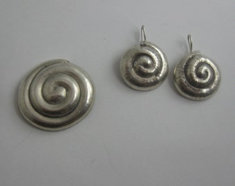 Puede incluir: Un conjunto de tres pendientes de plata con un diseño en espiral. Los pendientes están hechos de metal y tienen un acabado brillante.