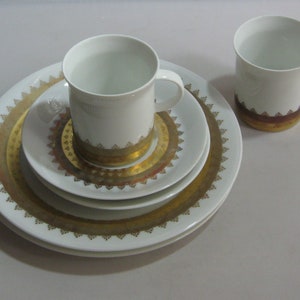 Könnte beinhalten: Ein weißes Tee-Set mit goldenen Verzierungen und einem passenden größeren Teller. Das Set hat ein zartes Blumenmuster in Gold.