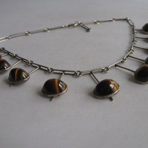 May include: A silver necklace with a chain and multiple dangling tiger's eye stones.