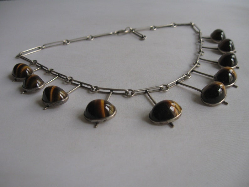 May include: A silver necklace with a chain and multiple dangling tiger's eye stones.