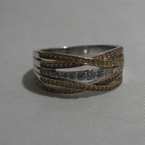 Könnte beinhalten: Ein silberner Ring mit drei Bändern aus pavé-besetzten Diamanten. Die Bänder sind ineinander verschlungen und die Diamanten sind klar, champagnerfarben und weiß.