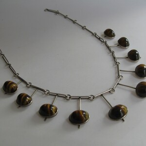 May include: A silver necklace with a chain and nine dangling tiger's eye stones.