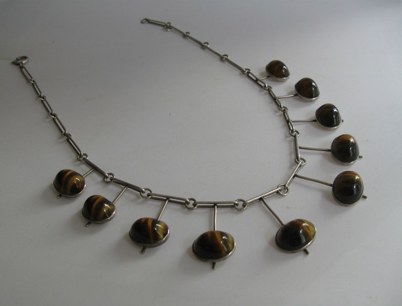 May include: A silver necklace with a chain and nine dangling tiger's eye stones.