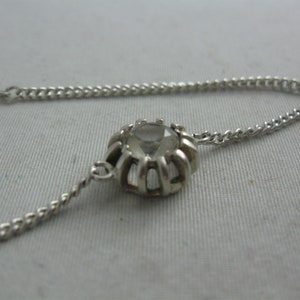 May include: A silver chain bracelet with a clear crystal stone set in a silver bezel.