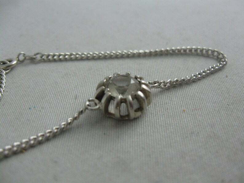 May include: A silver chain bracelet with a clear crystal stone set in a silver bezel.