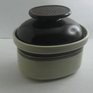 May include: A brown and white ceramic sugar bowl with a lid. The lid has a textured design.