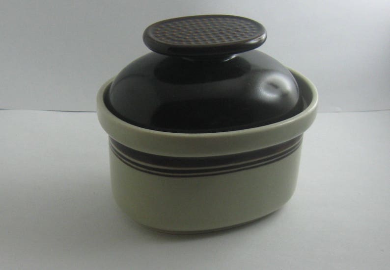 May include: A brown and white ceramic sugar bowl with a lid. The lid has a textured design.