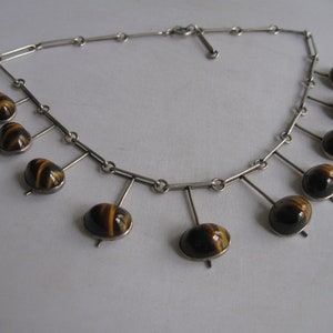 May include: A silver necklace with a chain and multiple dangling tiger's eye stones.