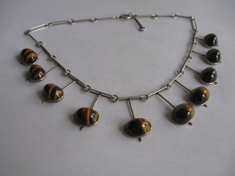 May include: A silver necklace with a chain and multiple dangling tiger's eye stones.