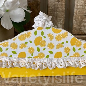 May include: A yellow wooden box with a lemon print and white crocheted trim. The box is shaped like a pie crust and has the text "varietyislife" on the bottom.