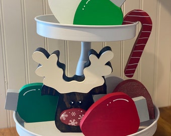 May include: A white tiered tray with a wooden reindeer, candy cane, and red, green, and white light bulb ornaments.