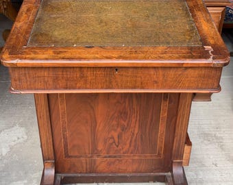 Könnte beinhalten: Antiker Schreibtisch aus Holz mit dunkelbraunem Finish. Der Schreibtisch hat eine rechteckige Oberseite mit einem grünen Ledereinsatz, eine kleine Schublade und einen Unterschrank. Der Schreibtisch hat ein klassisches Design mit dekorativen Beinen und einer erhöhten Rückseite.