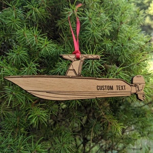 May include: Wooden ornament shaped like a boat with a red ribbon. The boat has a motor and the text "CUSTOM TEXT" is engraved on the side.