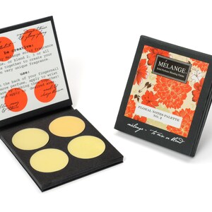 May include: A black box with a floral design and the text "MELANGE. Solid Perfume Blending Palette" and "FLORAL NOTES PALETTE NO. 2". The box is open and shows four round, yellow-colored solid perfume discs.