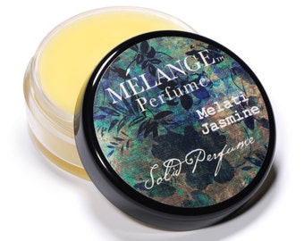 May include: A small round jar of solid perfume with a black lid. The lid has a floral design and the text "MELANGE™ Perfume Melati Jasmine Solid Perfume".