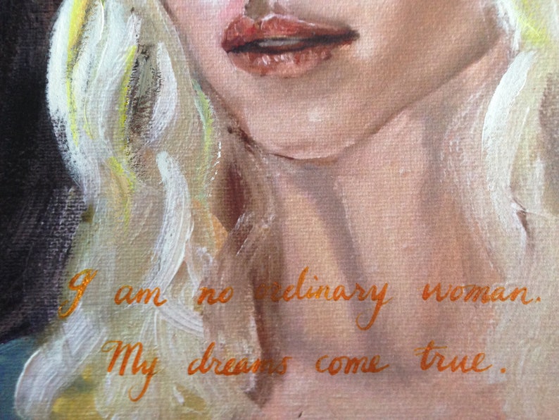 May include: A painting of a woman with blonde hair and red lips. The text "I am no ordinary woman. My dreams come true." is written in orange paint on the woman's chest.