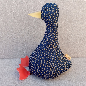 May include: A blue and gold polka dot fabric duck doorstop with red fabric feet. The duck has a yellow beak and a small tag that says "Cool Canard".