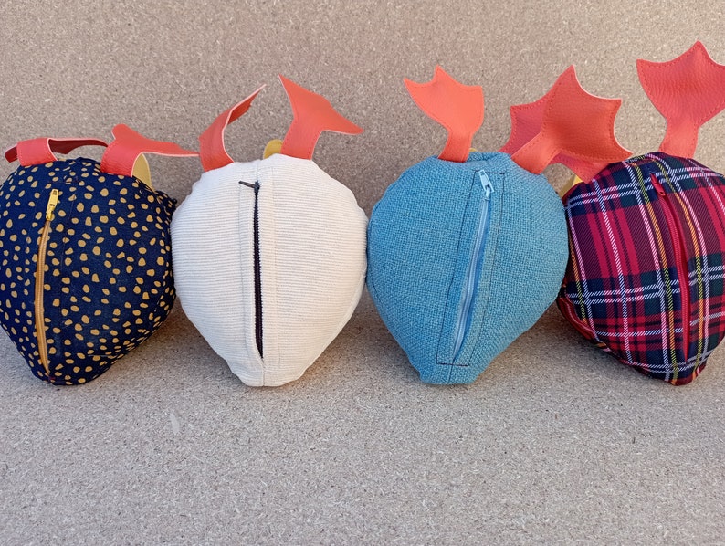 May include: Four plush heart-shaped pillows with different fabric patterns. Each pillow has a zipper closure and a red felt accent on top.