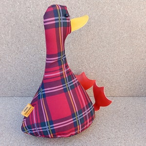 May include: Red and black plaid duck plush toy with a yellow beak and red wings. The toy has a label that says "Cool Canard".