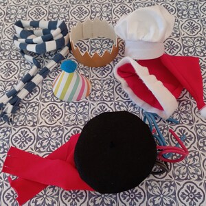 May include: A collection of colorful hats and headbands, including a red and white Santa hat, a blue and white striped headband, a black beret, a white chef's hat, and a colorful party hat.