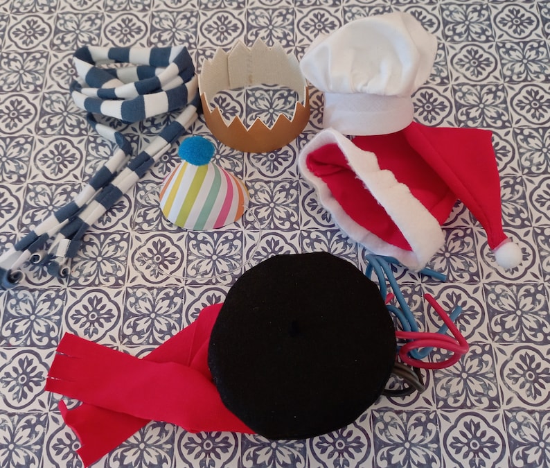 May include: A collection of colorful hats and headbands, including a red and white Santa hat, a blue and white striped headband, a black beret, a white chef's hat, and a colorful party hat.