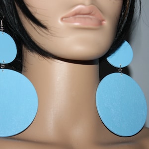 May include: A pair of large, round, light blue earrings. Each earring has two circles, one slightly smaller than the other, connected by a silver chain.