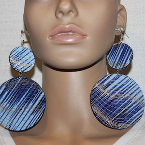 May include: A pair of large, round, blue and silver earrings with a geometric pattern. The earrings are made of wood and have a silver wire hanger.