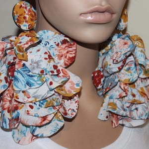 Puede incluir: Pendientes grandes con estampado floral en blanco, azul, naranja y amarillo. Los pendientes tienen un perno circular y un diseño en cascada en capas. Un accesorio llamativo.