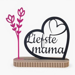 Pode incluir: Uma peça decorativa de madeira com as palavras "Liefste mama" recortadas em forma de coração. Um design floral rosa está à esquerda. A peça assenta numa base de madeira.
