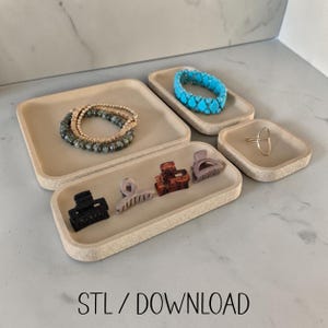 Op de afbeelding: Een set van vier beige rechthoekige en vierkante schaaltjes met sieraden en haaraccessoires, waaronder een kralenarmband, een turquoise armband, een gouden ring en vier haarklemmen. De tekst STL / DOWNLOAD staat onderaan afgebeeld.