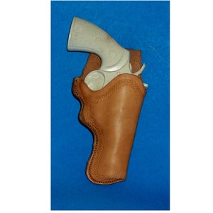 May include: A brown leather holster with a white handgun inside. The holster has a stitched design and is on a blue background.