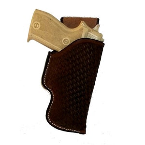 May include: A brown leather holster with a woven pattern. A light brown handgun is inside the holster.