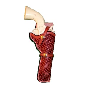 May include: A brown leather holster with a woven pattern and a brass button. The holster is designed to hold a pistol.