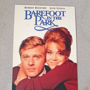 May include: A vintage VHS tape cover featuring Robert Redford and Jane Fonda in a close embrace. The title "BAREFOOT IN THE PARK" is displayed in blue lettering with a stylized blue infinity symbol.