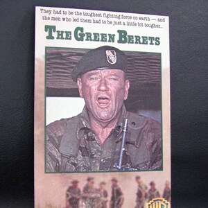 Puede incluir: Una carátula de cinta VHS vintage para la película "Los Boinas Verdes" protagonizada por John Wayne. La carátula presenta una foto de John Wayne con uniforme y un gorro verde, con una expresión seria. El texto "Los Boinas Verdes" está en letras grandes y en negrita en la parte superior de la carátula.