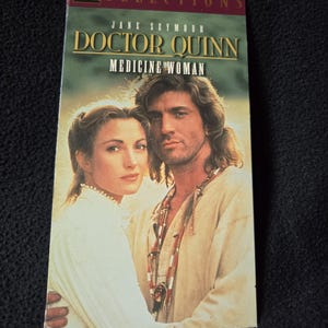 May include: A VHS tape for the television series "Doctor Quinn, Medicine Woman" featuring Jane Seymour and Joe Lando. The cover has a portrait of the two actors. The title is in gold lettering with a green background.