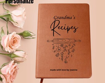 May include: A brown recipe journal with the words "Grandma's Recipes" in elegant script. A rolling pin and floral design are below the title. The phrase "made with love by: joanna" is at the bottom. A pink ribbon bookmark is visible.