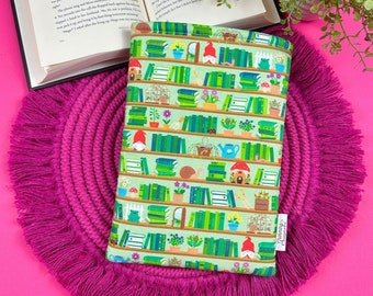 Puede incluir: Funda para lector electrónico de color verde con un patrón repetido de libros, gnomos, flores y caracoles. La funda tiene un borde blanco y el texto "Reading Charmer" en la esquina inferior derecha.