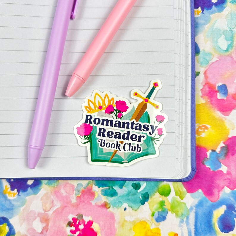 May include: A sticker with a whimsical design featuring a book, a sword, flowers, and a crown. The text reads "Romantasy Reader Book Club".