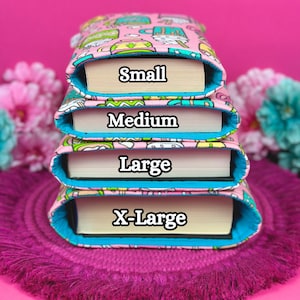 May include: Four book covers stacked on top of each other, with the words "Small", "Medium", "Large", and "X-Large" printed on each cover. The covers are pink with a blue trim and a colorful pattern.