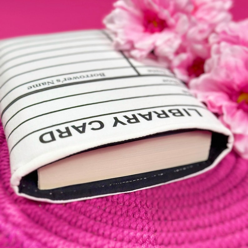 Foam padded book cover laying flat with a book inside.  The book sleeve has a design made to look like a library card.  It is great to take to book signings and events to collect author signatures.